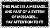 Stamp with the long-term nuclear waste warning message requirements from the Sandia National Laboratories report, shown one line at a time in white text on black spiky background. It reads 'This place is a message... and part of a system of messages... pay attention to it! Sending this message was important to us. We considered ourselves to be a powerful culture. This place is not a place of honor... No highly esteemed deed is commemorated here... nothing valued is here. What is here was dangerous and repulsive to us. This message is a warning about danger. The danger is in a particular location... it increases towards a center... the center of danger is here... of a particular size and shape, and below us. The danger is still present, in your time, as it was in ours. The danger is to the body, and it can kill. The form of the danger is an emanation of energy. The danger is unleashed only if you substantially disturb this place physically. This place is best shunned and left uninhabited.'