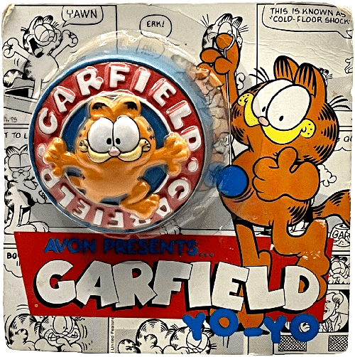 A yo-yo in original packaging. The toy is blue and red with a smiling 3D Garfield in the center. The packaging shows Garfield playing with a yo-yo and assorted black and white comic panels as the background.